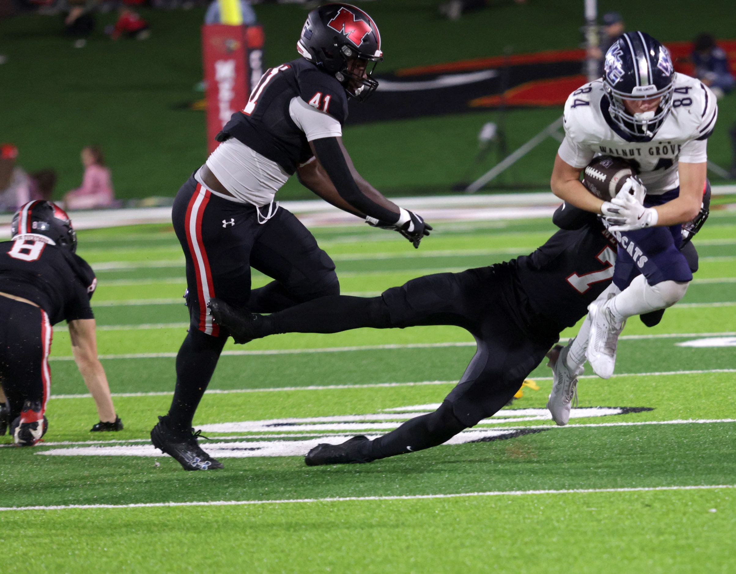 Walnut Grove player #84 Hayden Cooley is pulled down by Melissa player #7 Rocky Dunn during...