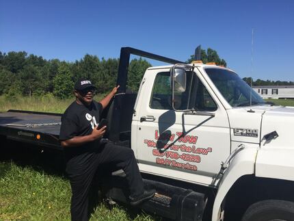 Dennis Smith Sr. stands next to the tow truck of the small company he owns. The truck is...