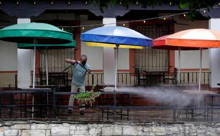 Workers clean the patio seating area of a restaurant on the River Walk that is preparing to...