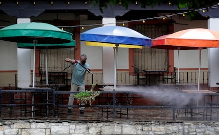 Workers clean the patio seating area of a restaurant on the River Walk that is preparing to...