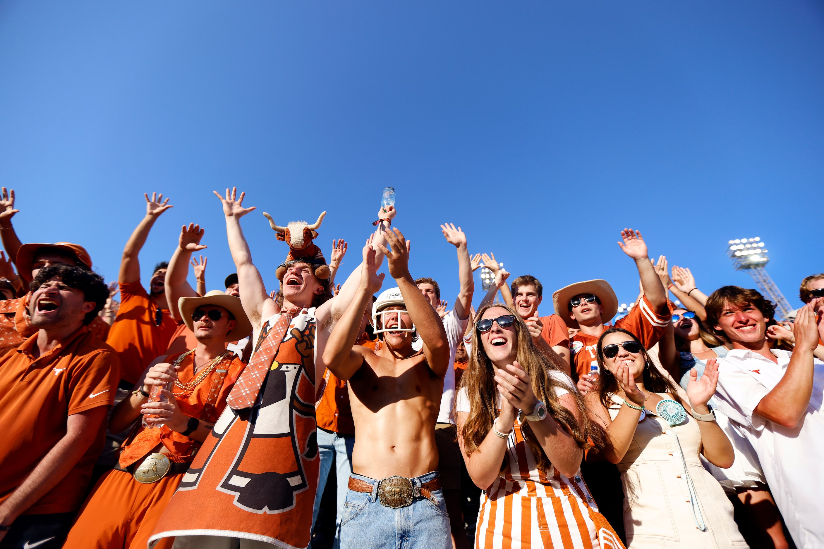 Texas Longhorns students cheer for the mascot who’s tossing cold bottles of water into the...