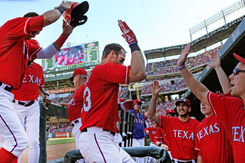 Texas outfielder Craig Gentry is greeted by teammates after scoring on an Ian Kinsler single...