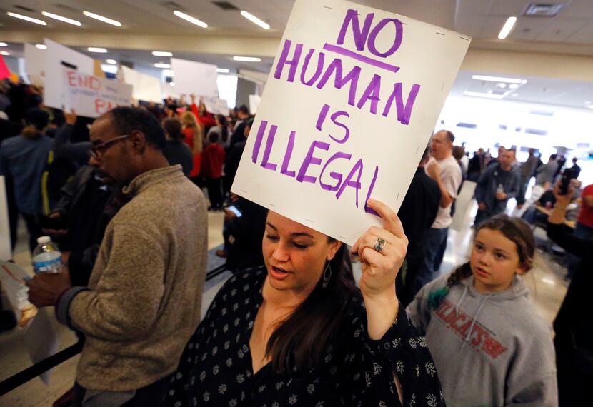 Protesters chanted as they held handmade signs at the international arrivals gate in...
