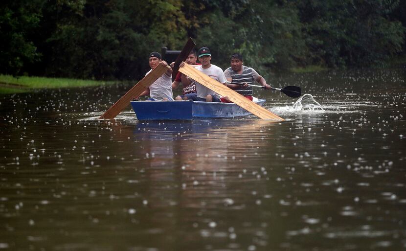 People use plywood to row a boat down Deats Road in Dickinson, Texas, Monday, Aug. 28, 2017,...