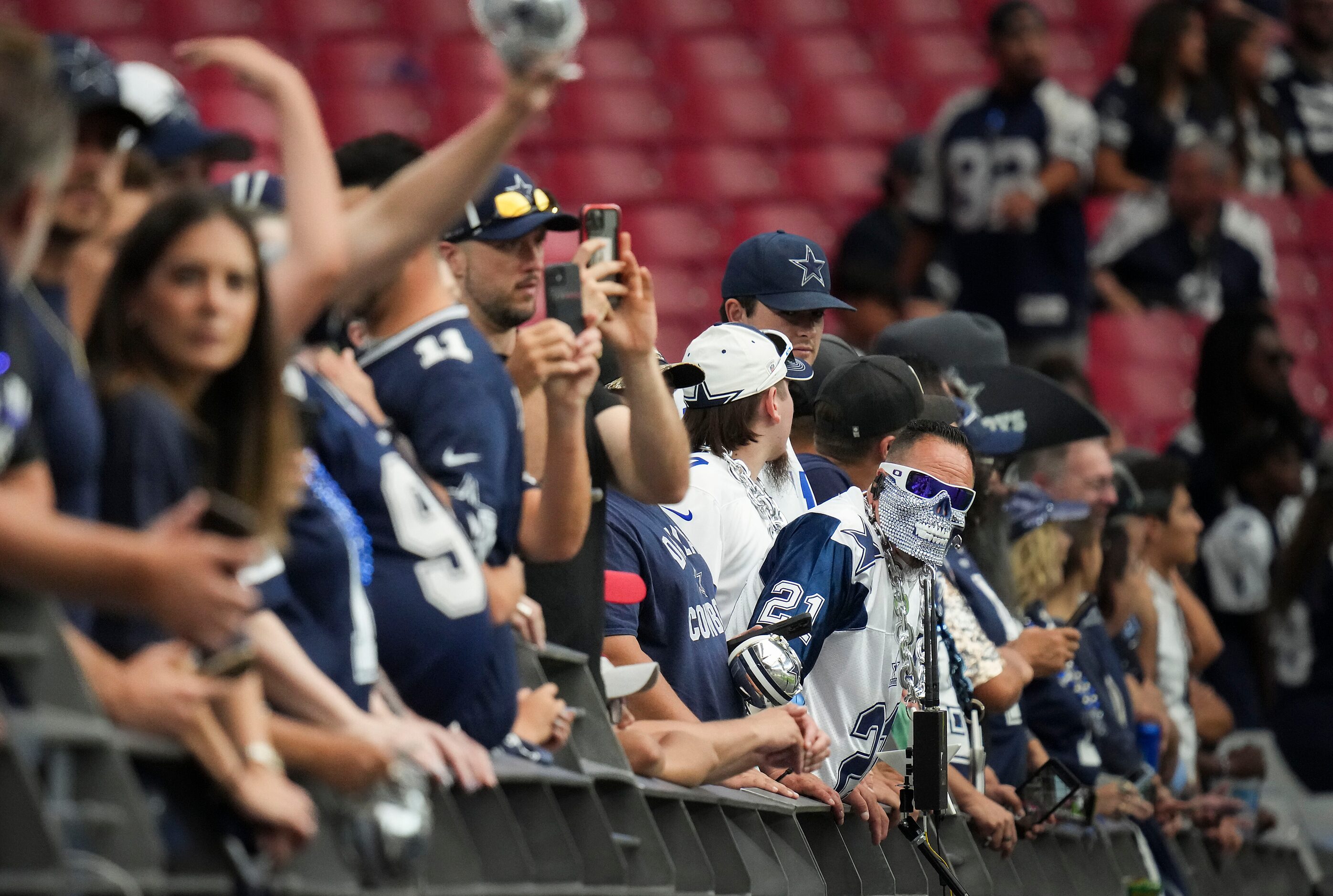 Dallas Cowboys line the front row to watch the team warm up before an NFL football game...