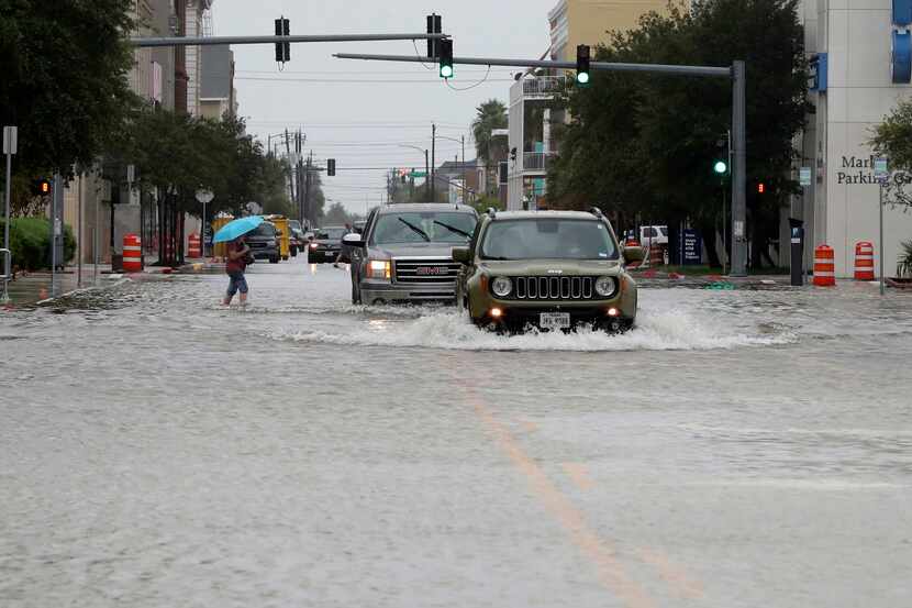 Cars make their way through high water at 20th and Market streets in Galveston on Friday.