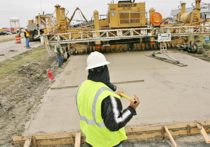 
A worker levels out concrete as crews pour the first concrete on an access road during...