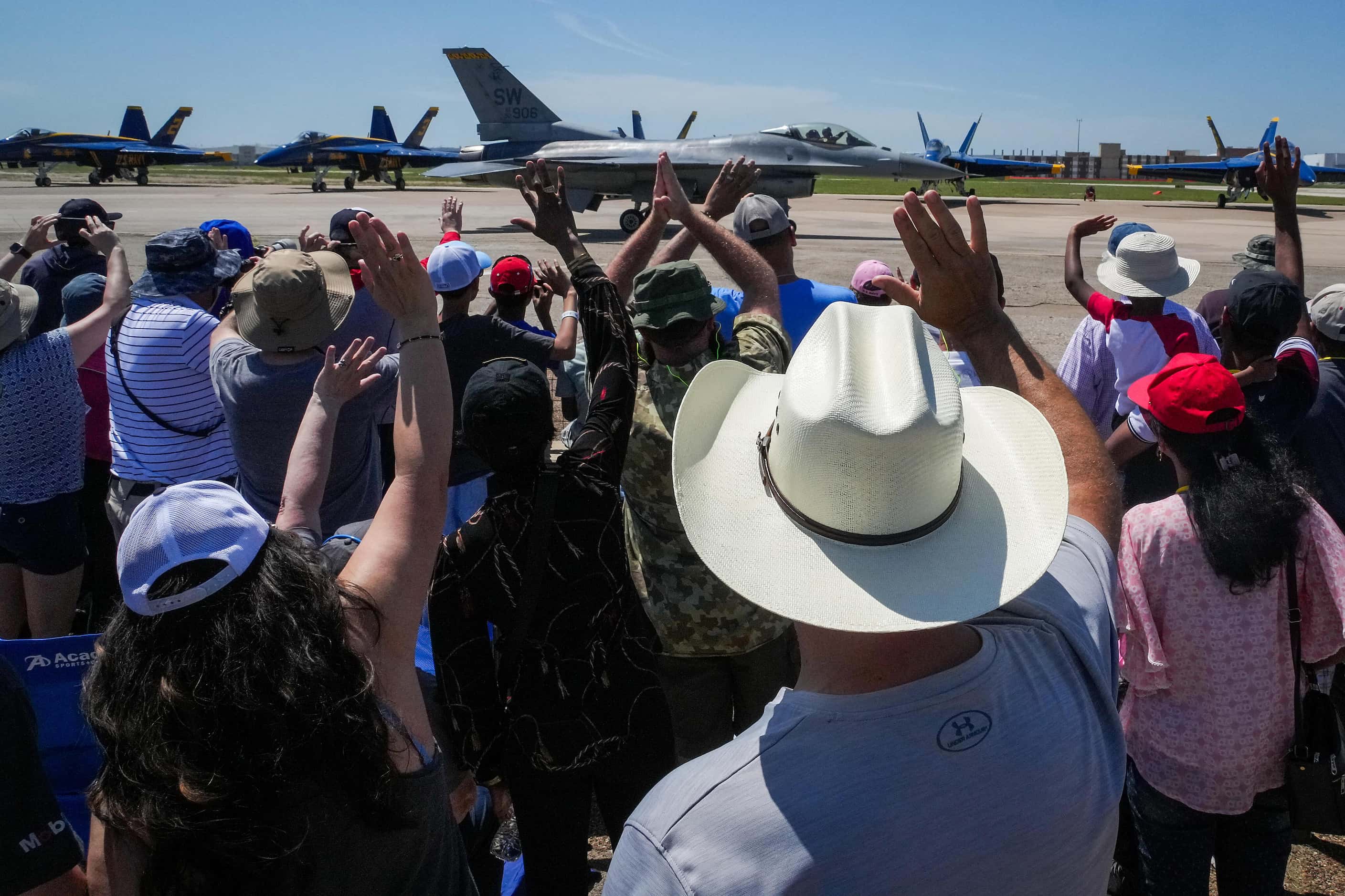 Spectators wave to Capt. Taylor Hiester as he taxis to takeoff for the U.S. Air Force F-16...