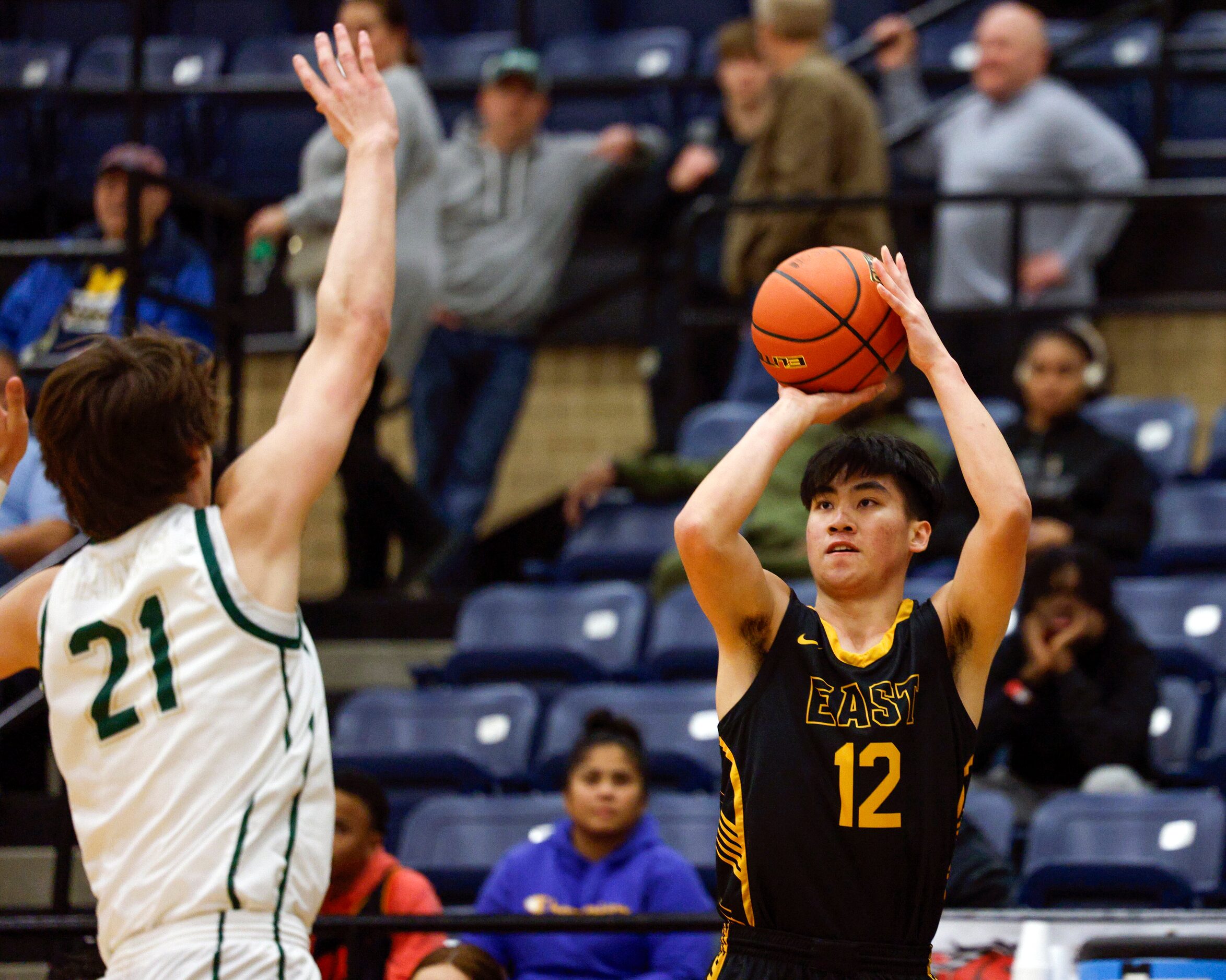 Plano East wing Jon Tran (12) shoots a three-pointer over Birdville guard Sawyer Dotson (21)...