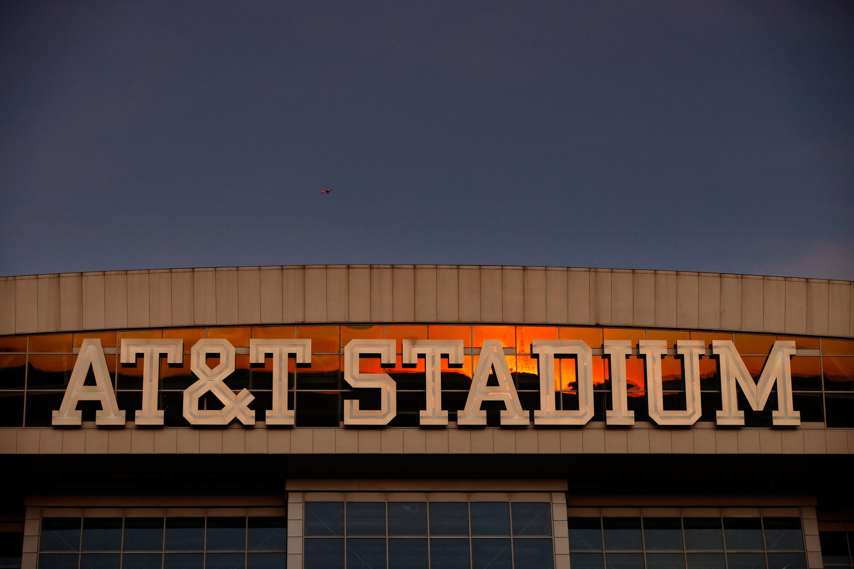 The sun sets on AT&T Stadium as pregame activities take place on the West Plaza before their...