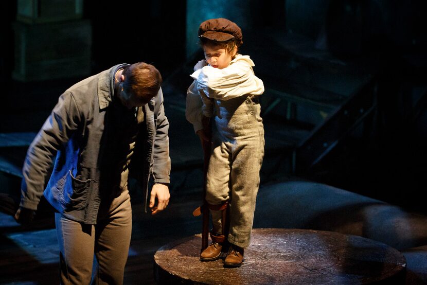 Alex Organ, as Bob Cratchit, takes center stage with Nina Ruby Gameros, as Tiny Tim, during...