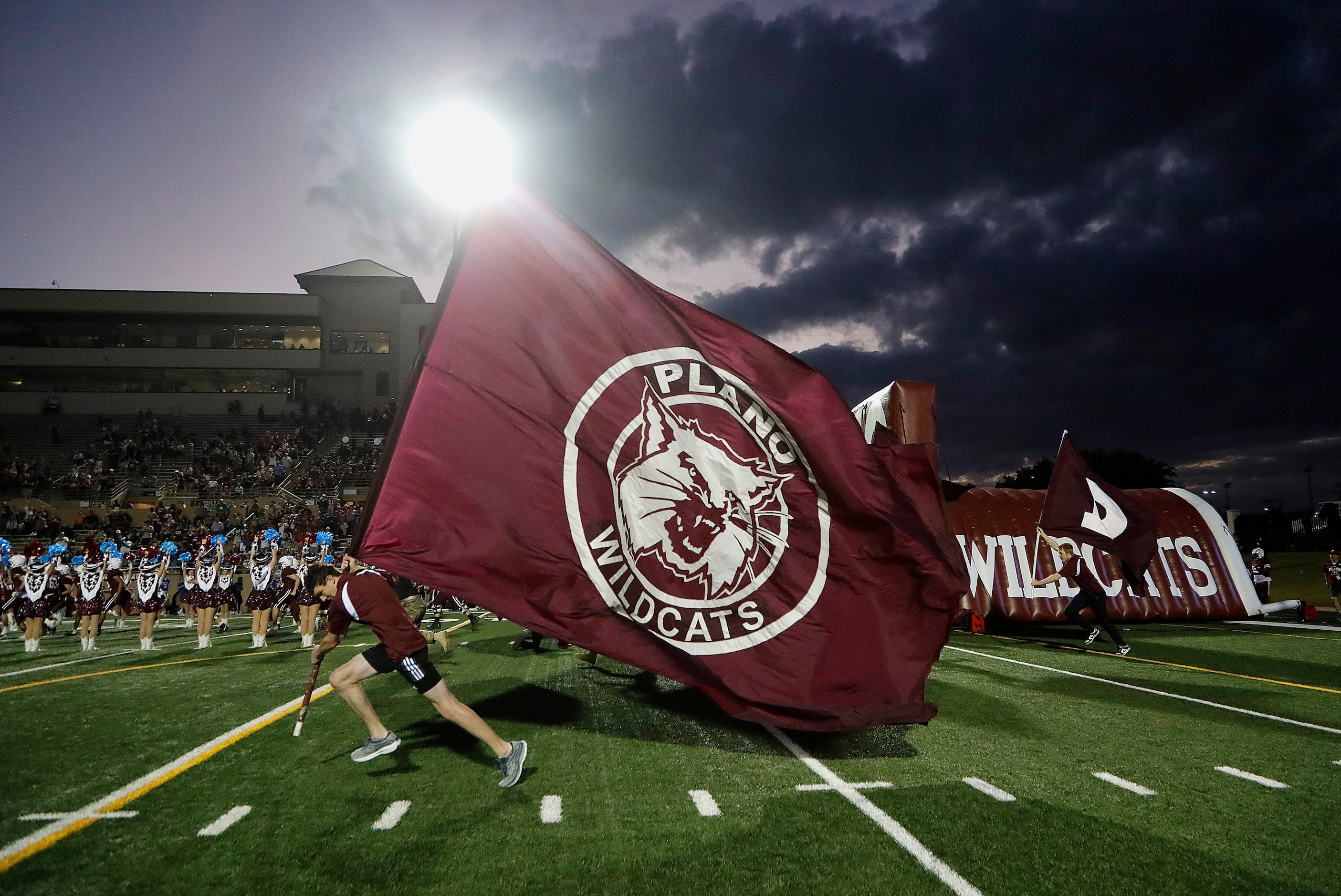 A Plano student runs the flag across the field as the team comes out before kickoff as...