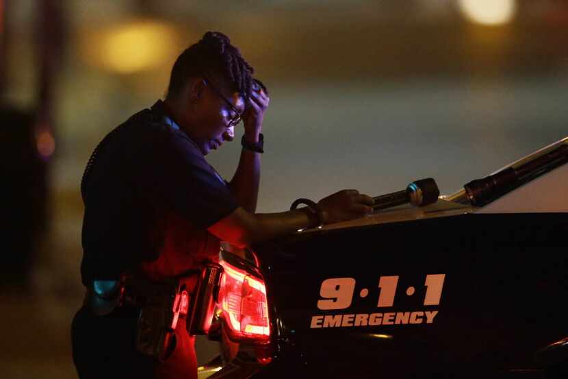 A Dallas police officer, who did not want to be identified, takes a moment as she guards an...