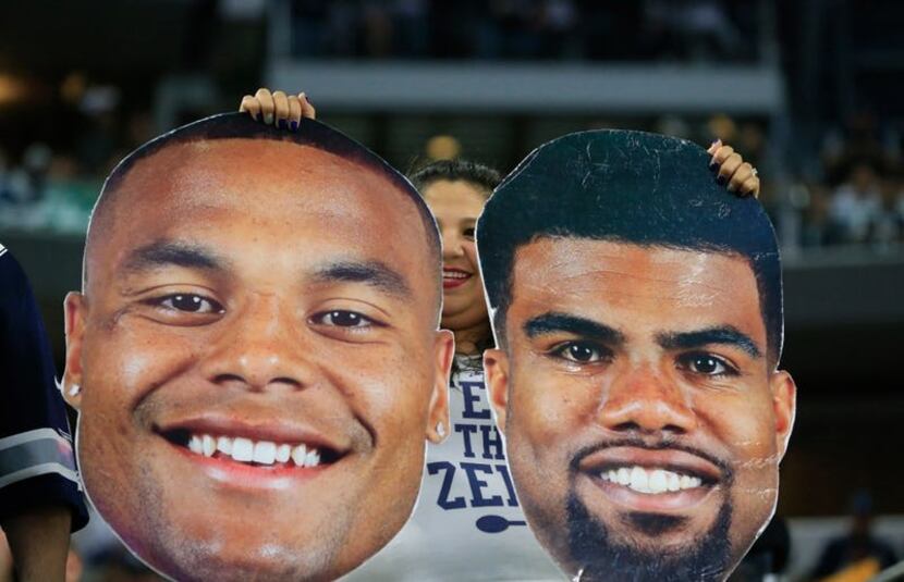Dallas Cowboys fans holds face posters of Dallas Cowboys quarterback Dak Prescott and...