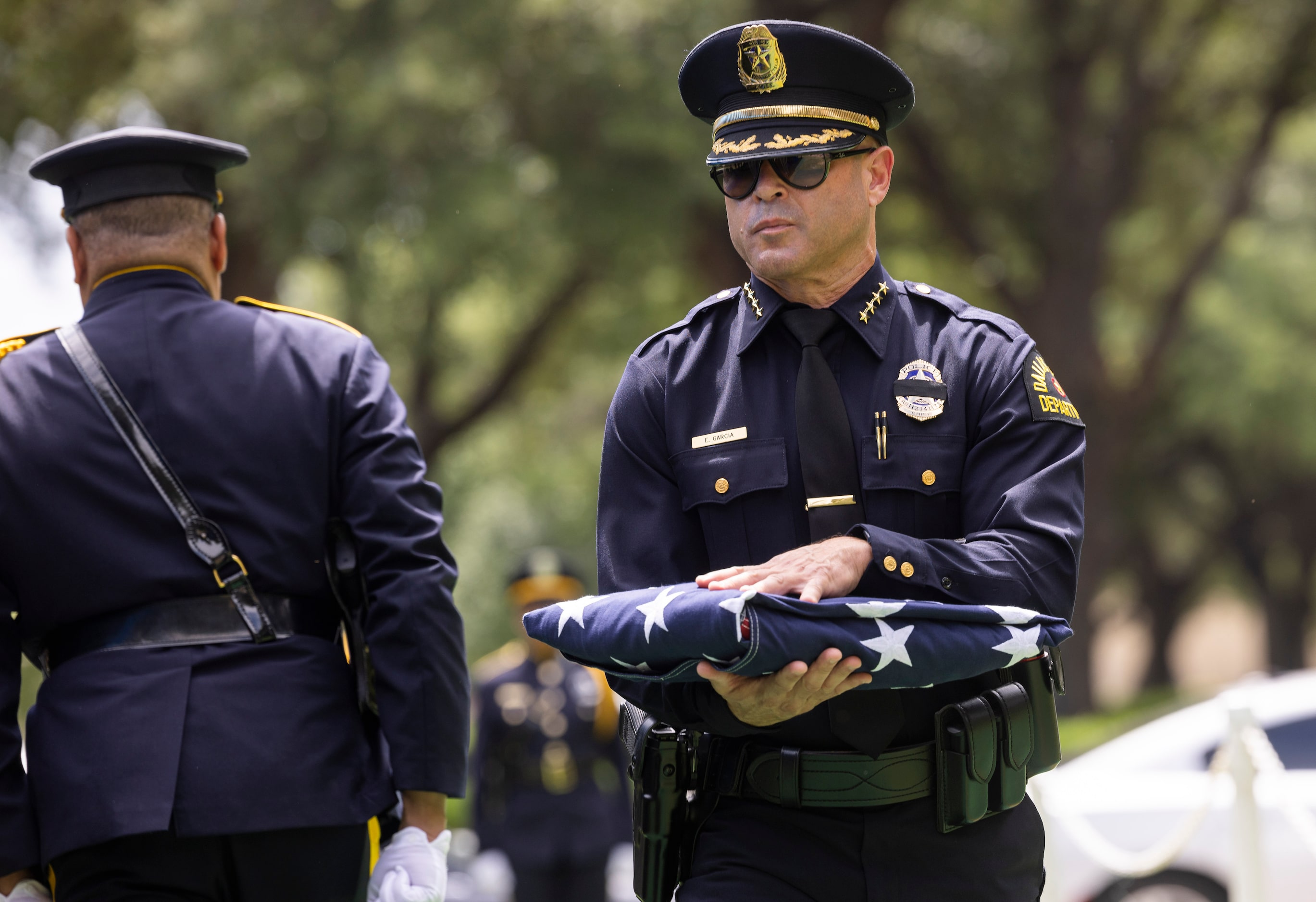 Dallas police Chief Eddie García carries a folded flag as the department renders full...