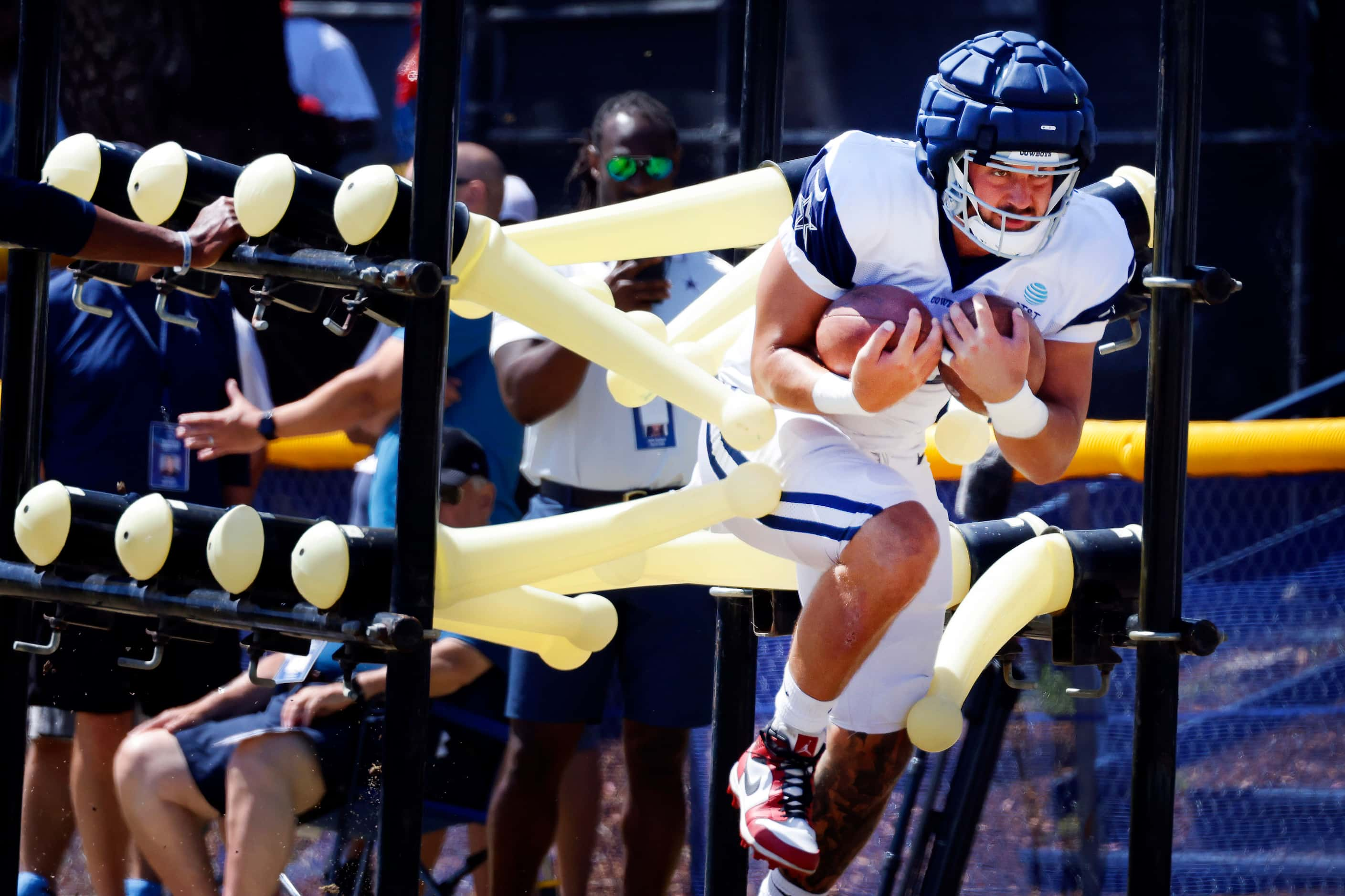 Dallas Cowboys tight end Jake Ferguson (87) runs through tackling batons during a training...