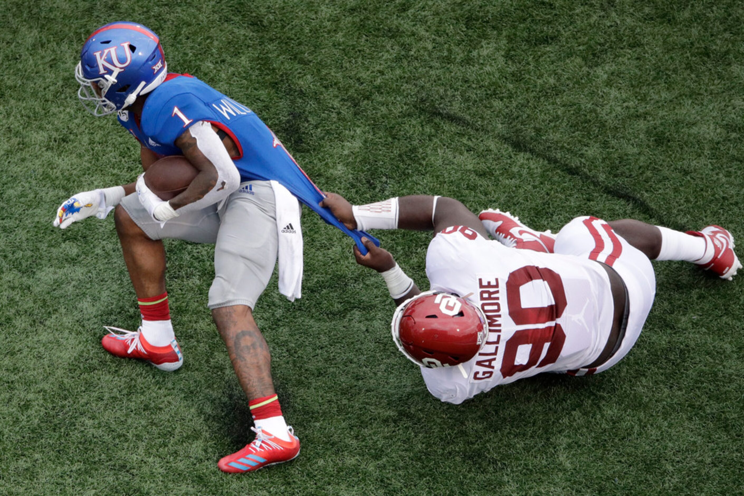 Oklahoma defensive lineman Neville Gallimore (90) tackles Kansas running back Pooka Williams...