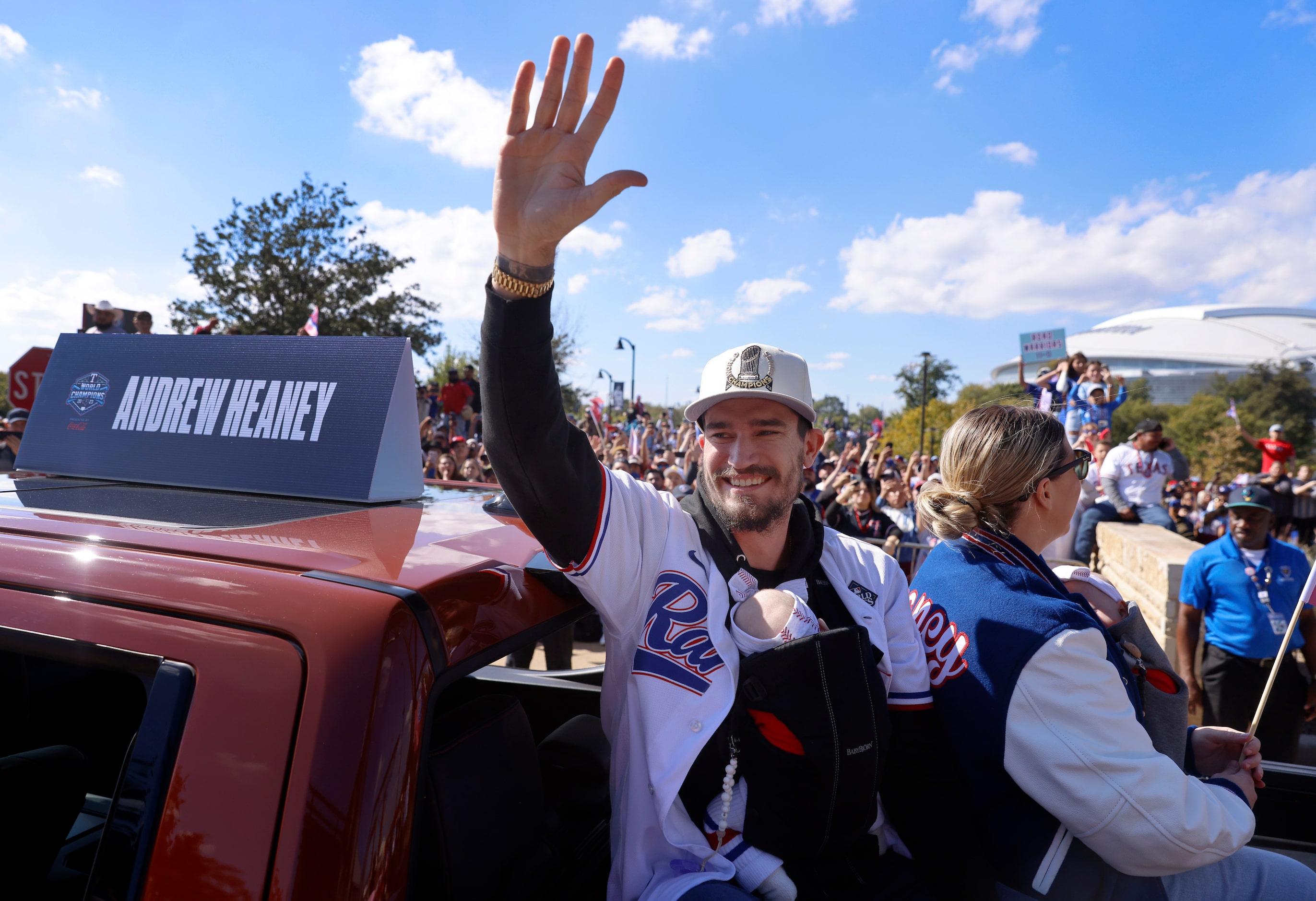 Texas Rangers pitcher Andrew Heaney waves to fans with his newborn wrapped around him during...