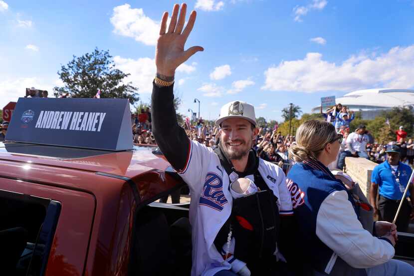 Texas Rangers pitcher Andrew Heaney waves to fans with his newborn wrapped around him during...