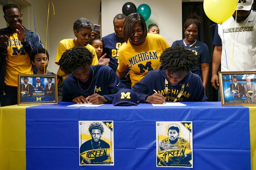 DeSoto's Gemon Green and twin brother German Green are watched by family as they sign a...