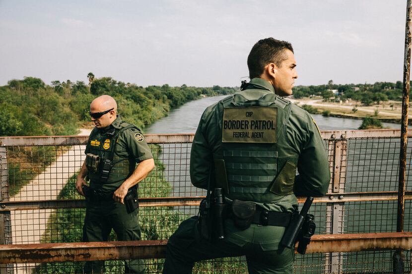 U.S. Border Patrol agents survey the Rio Grande River from an old bridge in Roma, TX, on May...