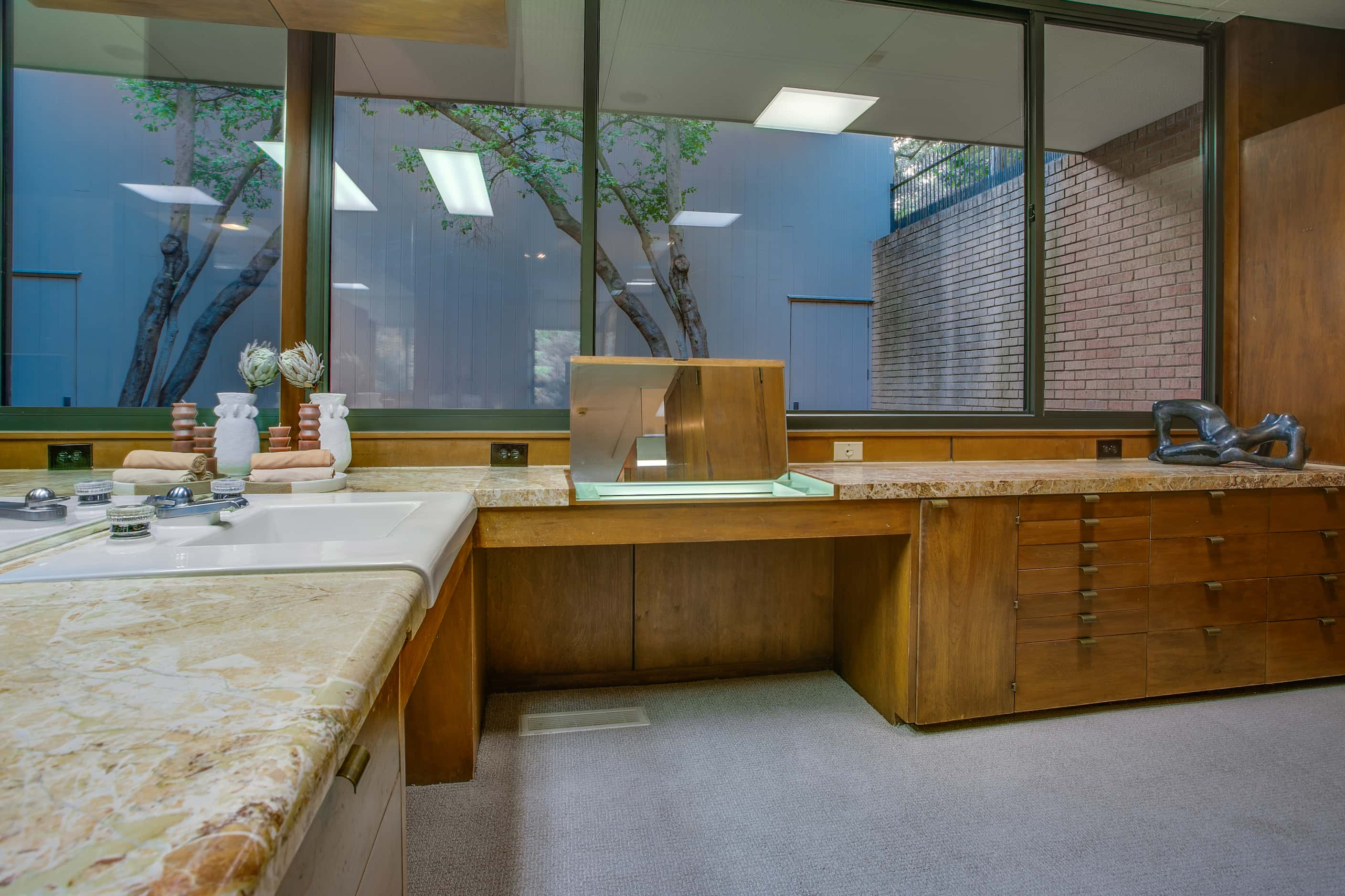 Bathroom with large windows, built-in cabinetry and a vanity