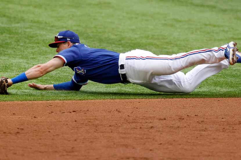 El segunda base de los Rangers de Texas, Nick Solak, se lanza por un batazo en el juego...