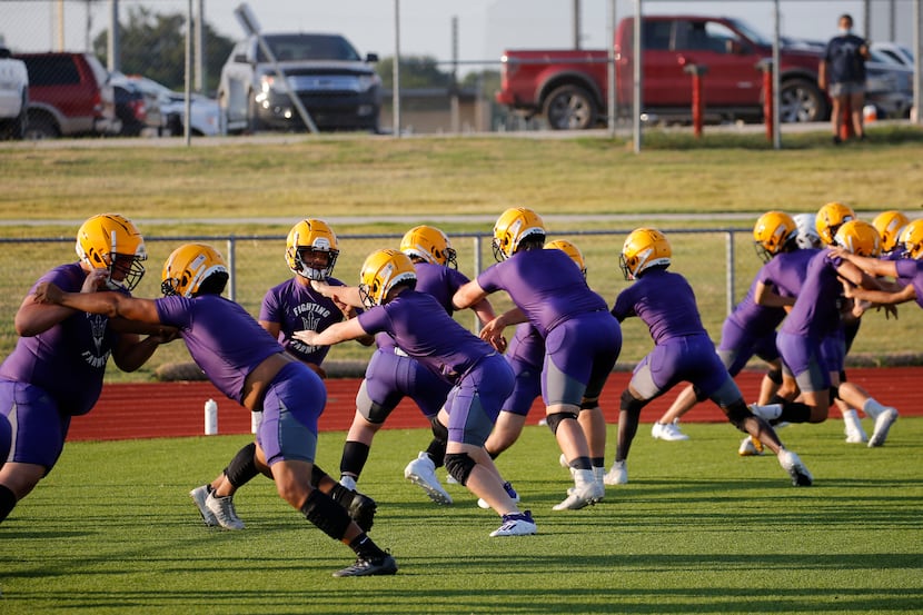 Linesmen run through a drill during the first day of high school football practice for 4A's...