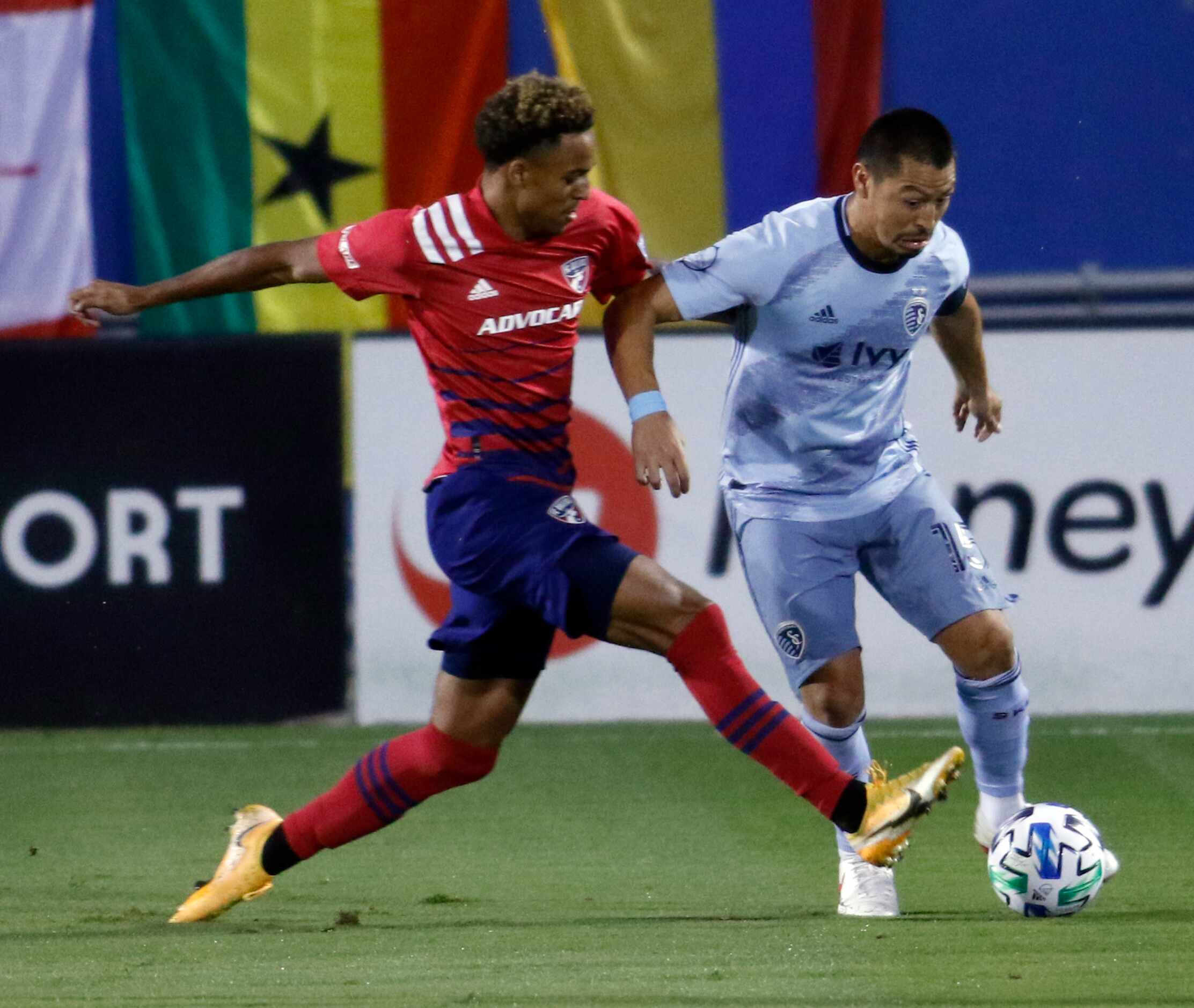 FC Dallas' Bryan Reynolds (14), left, challenges Sporting KC's Roger Espinoza (15) who works...
