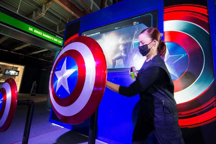 Una empleada sanitiza el escudo de Captain America durante una exhibición de Marvel Avengers...