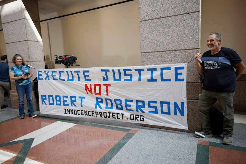 Amy Hedtke of Whitney and Bob Smilie of Duncanville hold a banner in front of a hearing room...