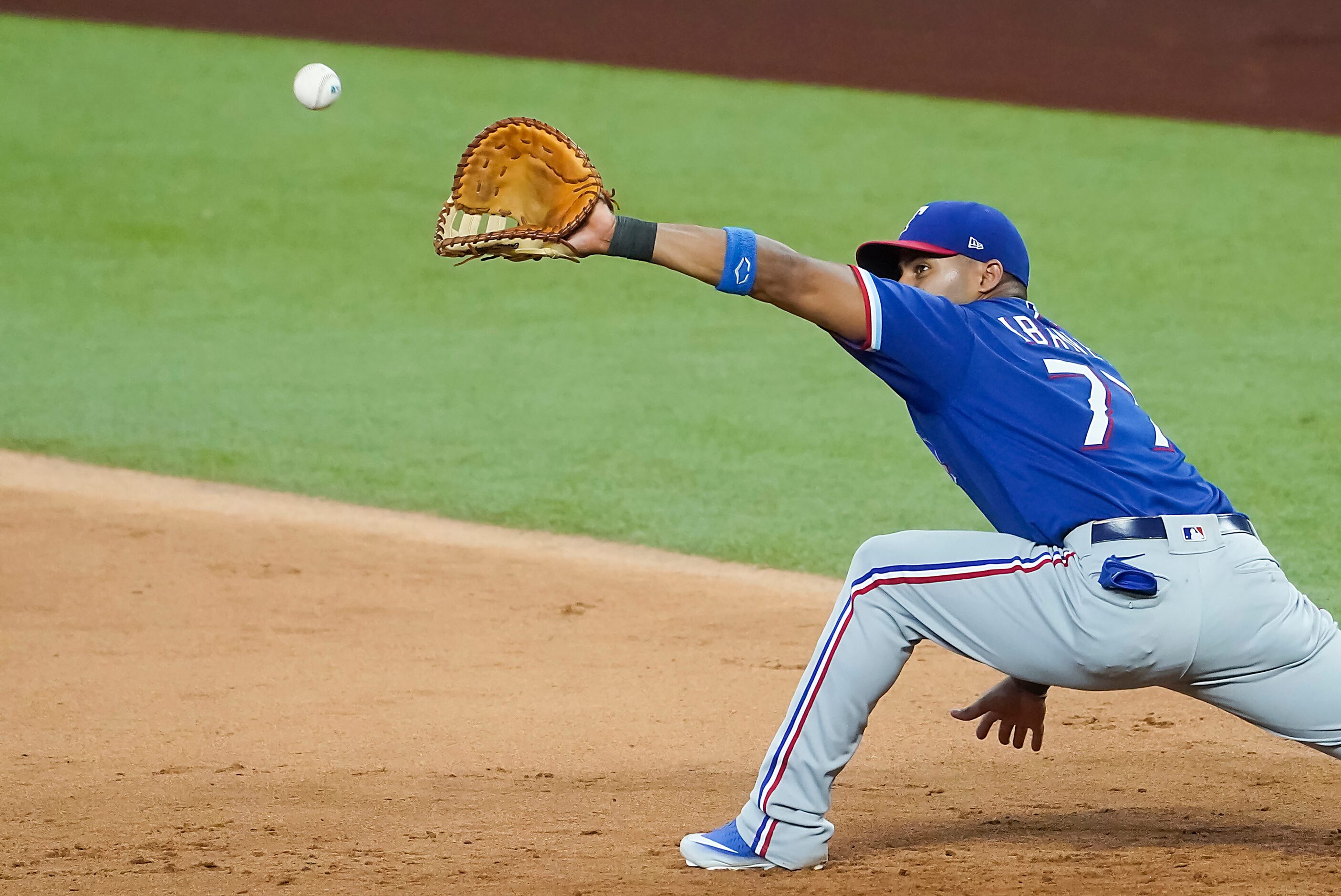 Texas Rangers infielder Andy Ibanez stretches for a throw at first base during a game...