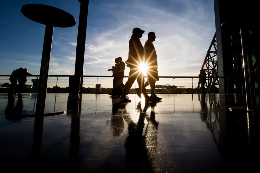 The sun sets as fans stroll along the open concourse at AT&T Stadium in Arlington before a...