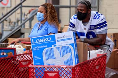 Dallas Cowboys linebacker Devin Harper waits to load a car with food and a fan during a...
