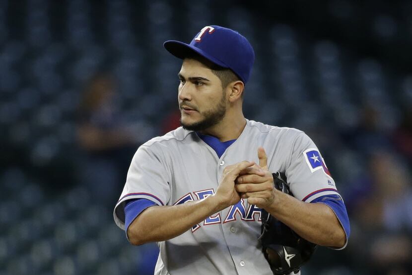 Texas Rangers starting pitcher Martin Perez squeezes the ball as he gets ready to pitch...