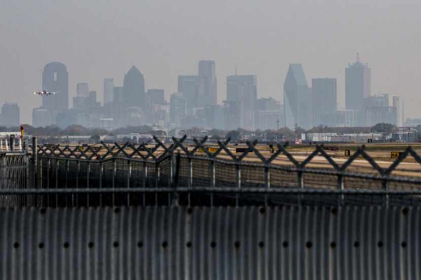 An airplane lands at Dallas Love Field Airport with the Dallas skyline in the background on...