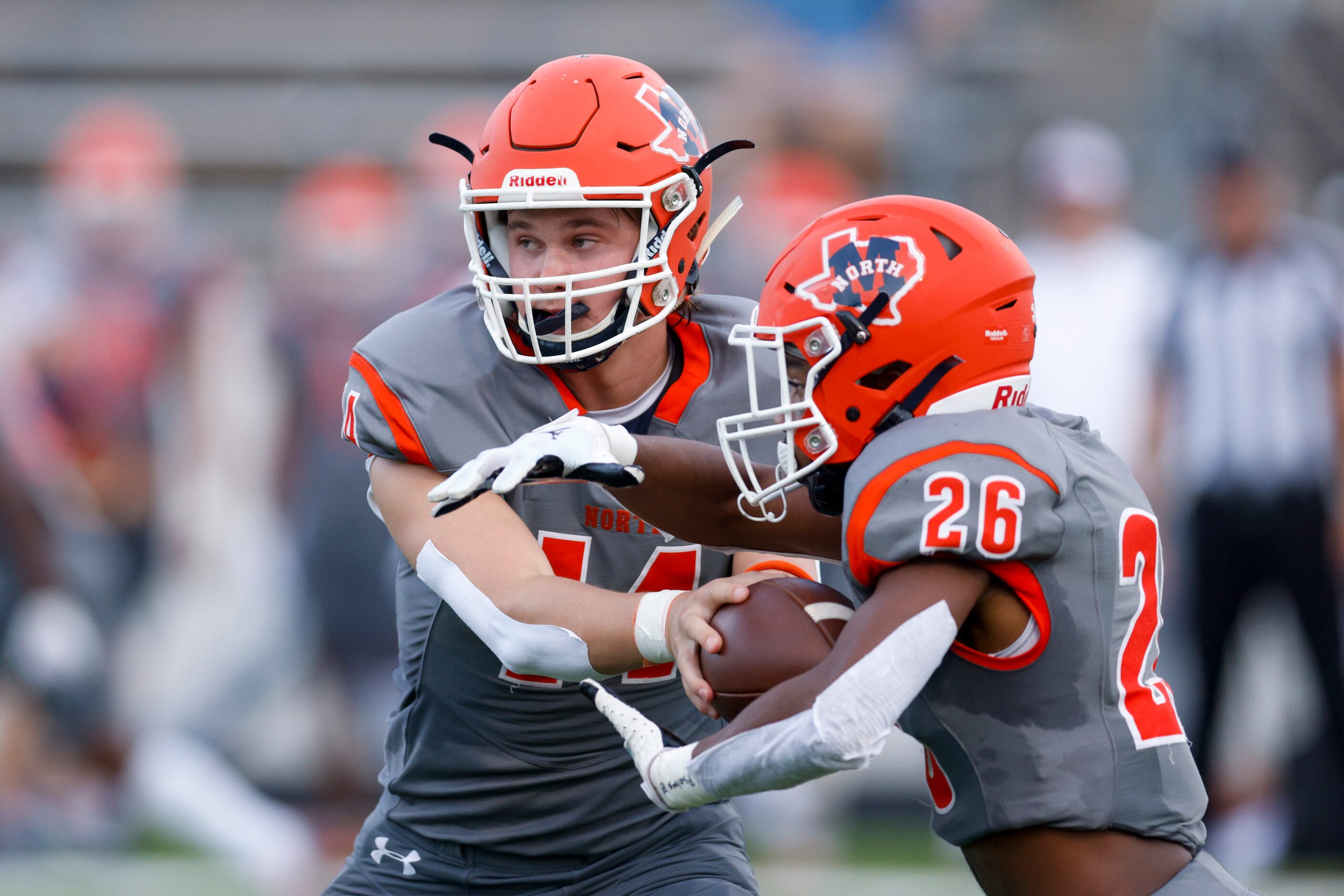 McKinney North quarterback Colin Hitchcock (14) hands the ball to running back Jayden Walker...