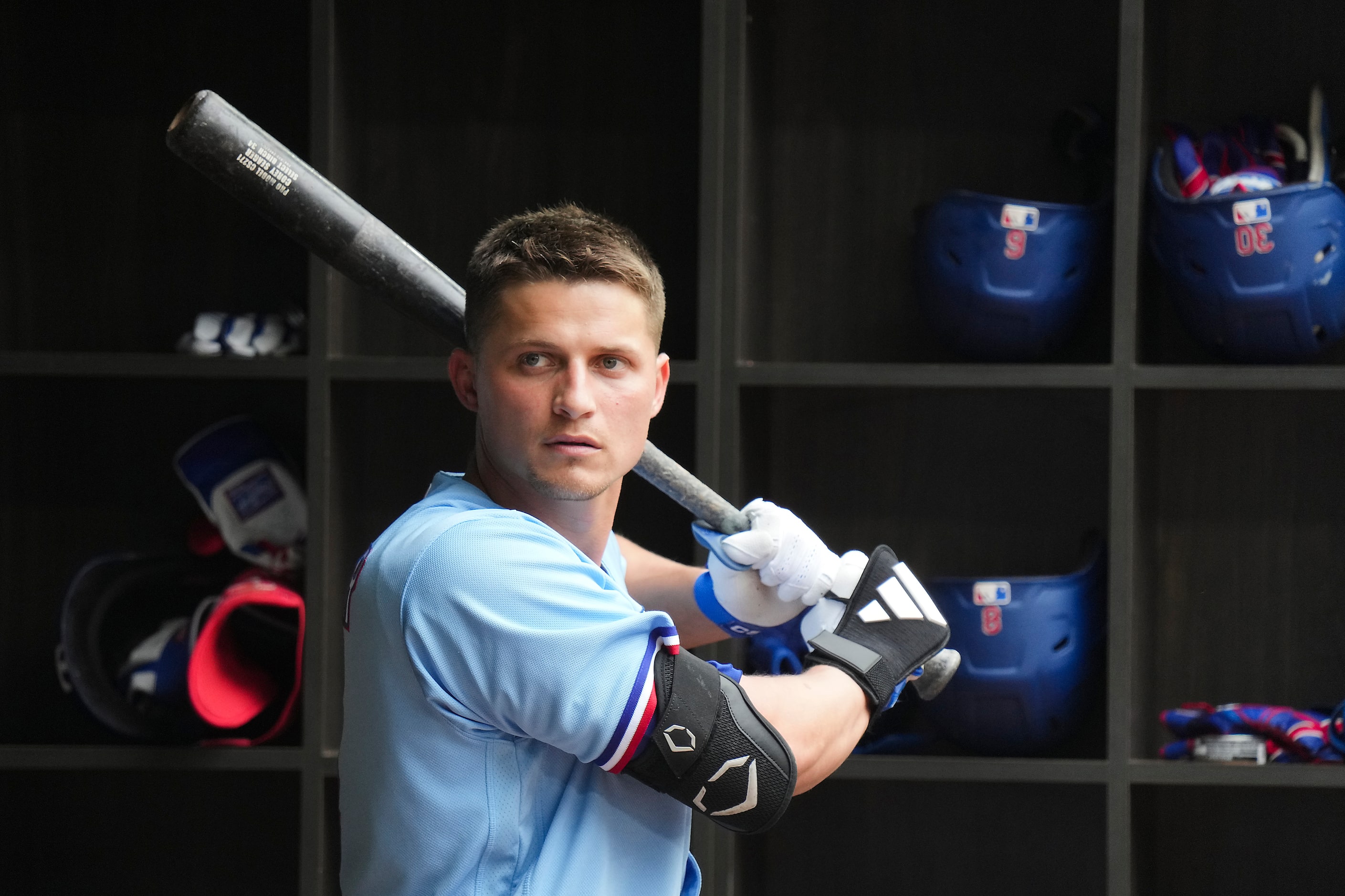 Texas Rangers designated hitter Corey Seager picks up a bat in the dugout during the seventh...