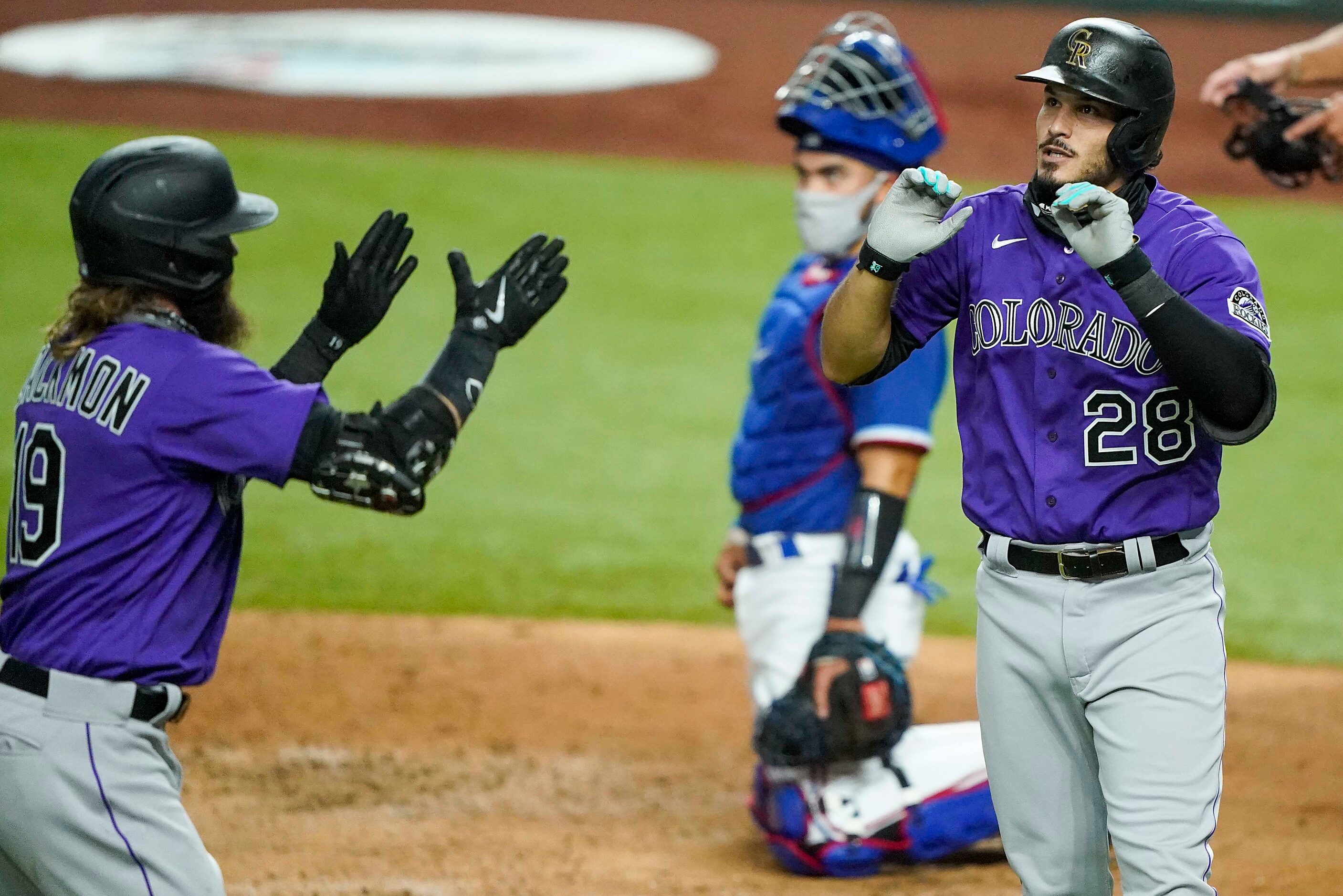 Texas Rangers catcher Robinson Chirinos watches Colorado Rockies third baseman Nolan Arenado...