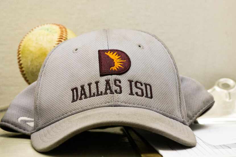 A DISD hat and baseball sit in the ticket booth during a high school baseball game between...