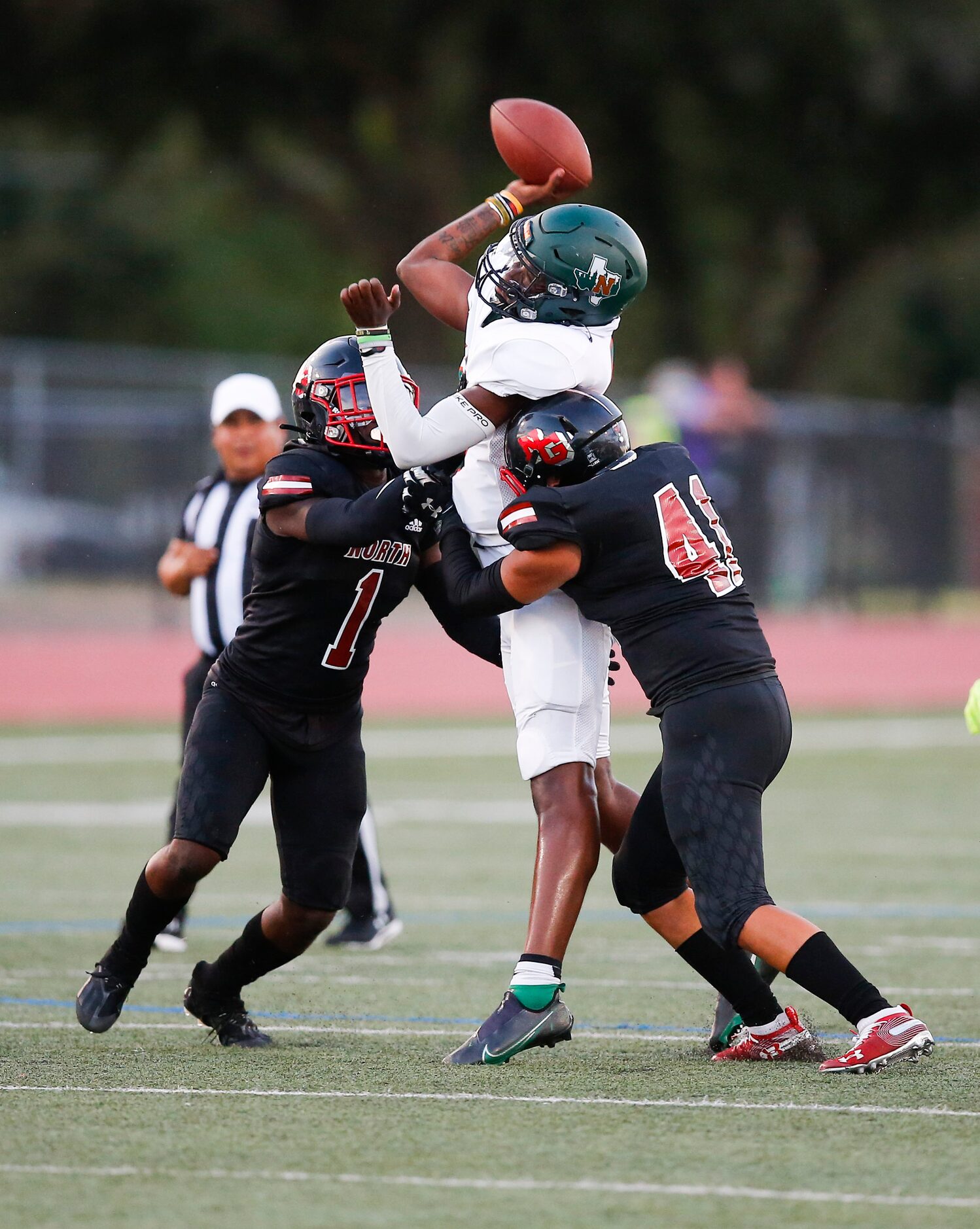 Garland Naaman Forest junior quarterback Tray Walton, center, attempts a pass as North...