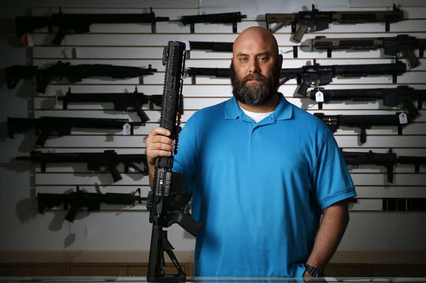Ro Carter holds an AR-15 rifle in his Plano shop, Mister Guns.