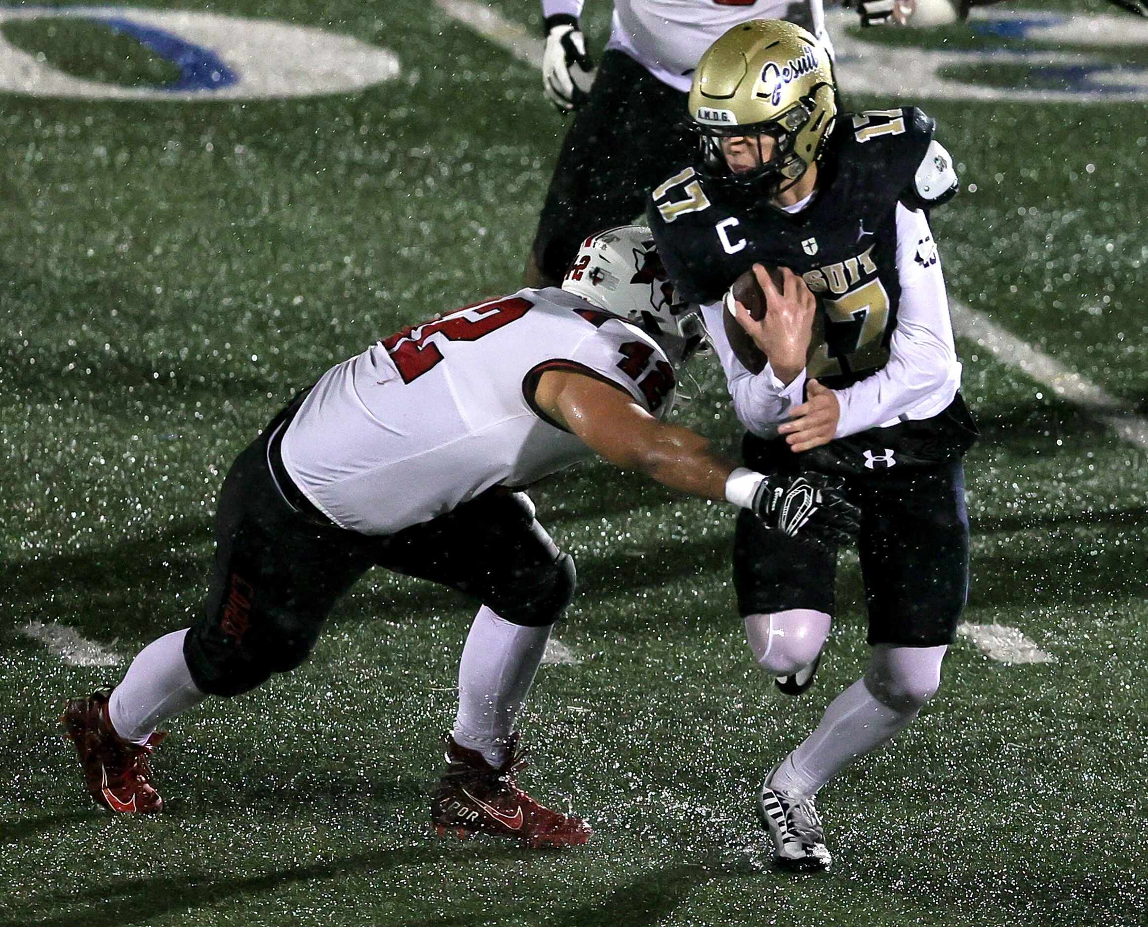 Jesuit quarterback Charlie Schmidt (17) tries to break a tackle from MacAthur linebacker...