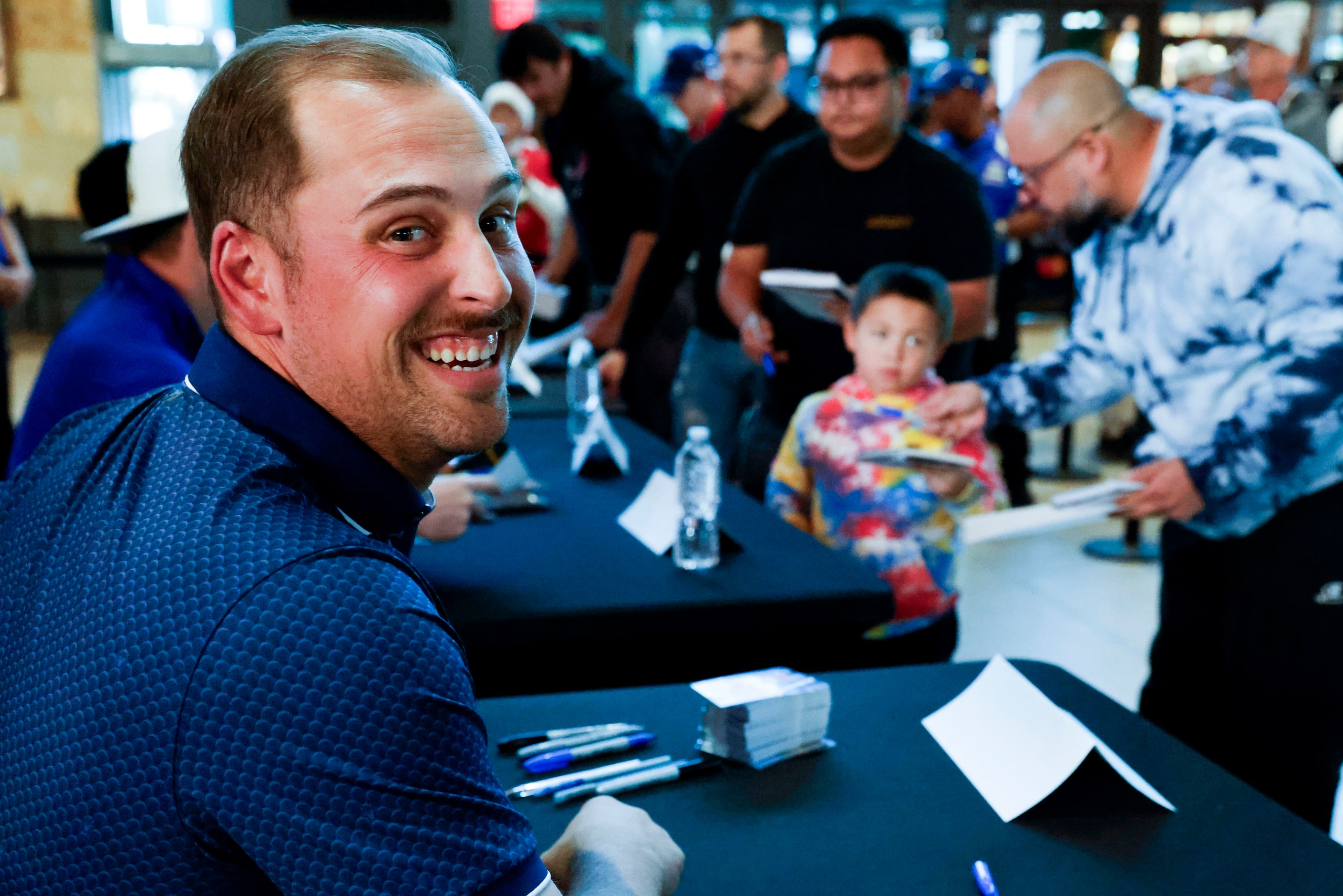 Texas Rangers first baseman Nathaniel Lowe looks back while signing autographs to fans...