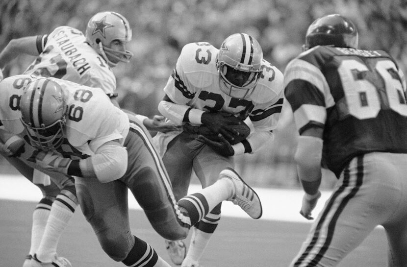 Dallas Cowboys star rookie running back Tony Dorsett (33) takes the ball from quarterback...