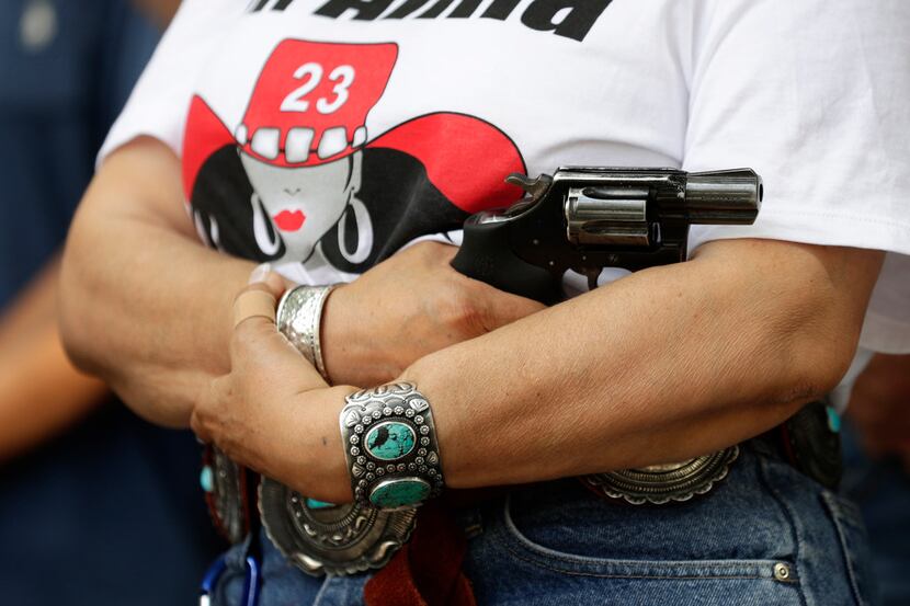 Dr. Alma Arredondo-Lynch holds a pistol as gun rights advocates gather outside the Texas...