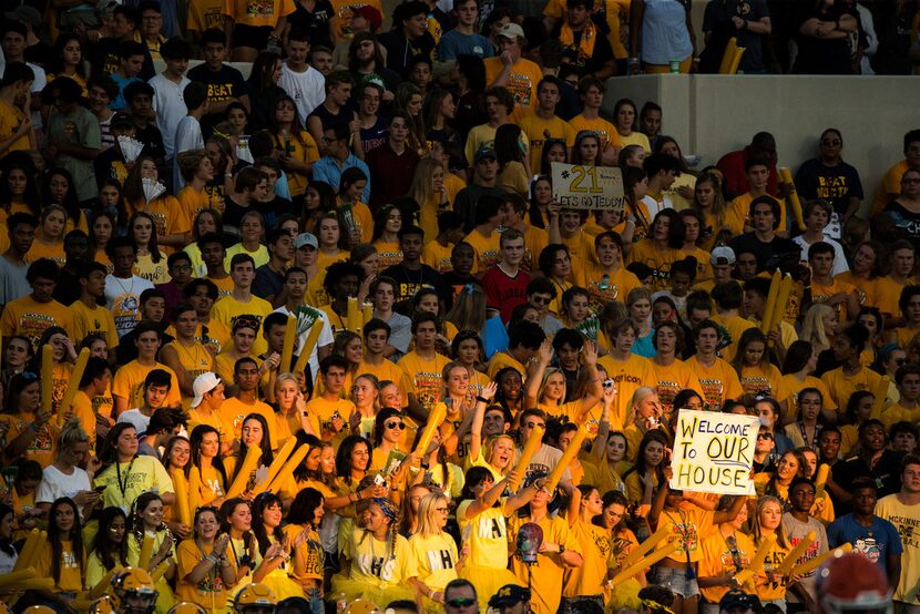 People in the McKinney student section cheer after a play during a high school football game...