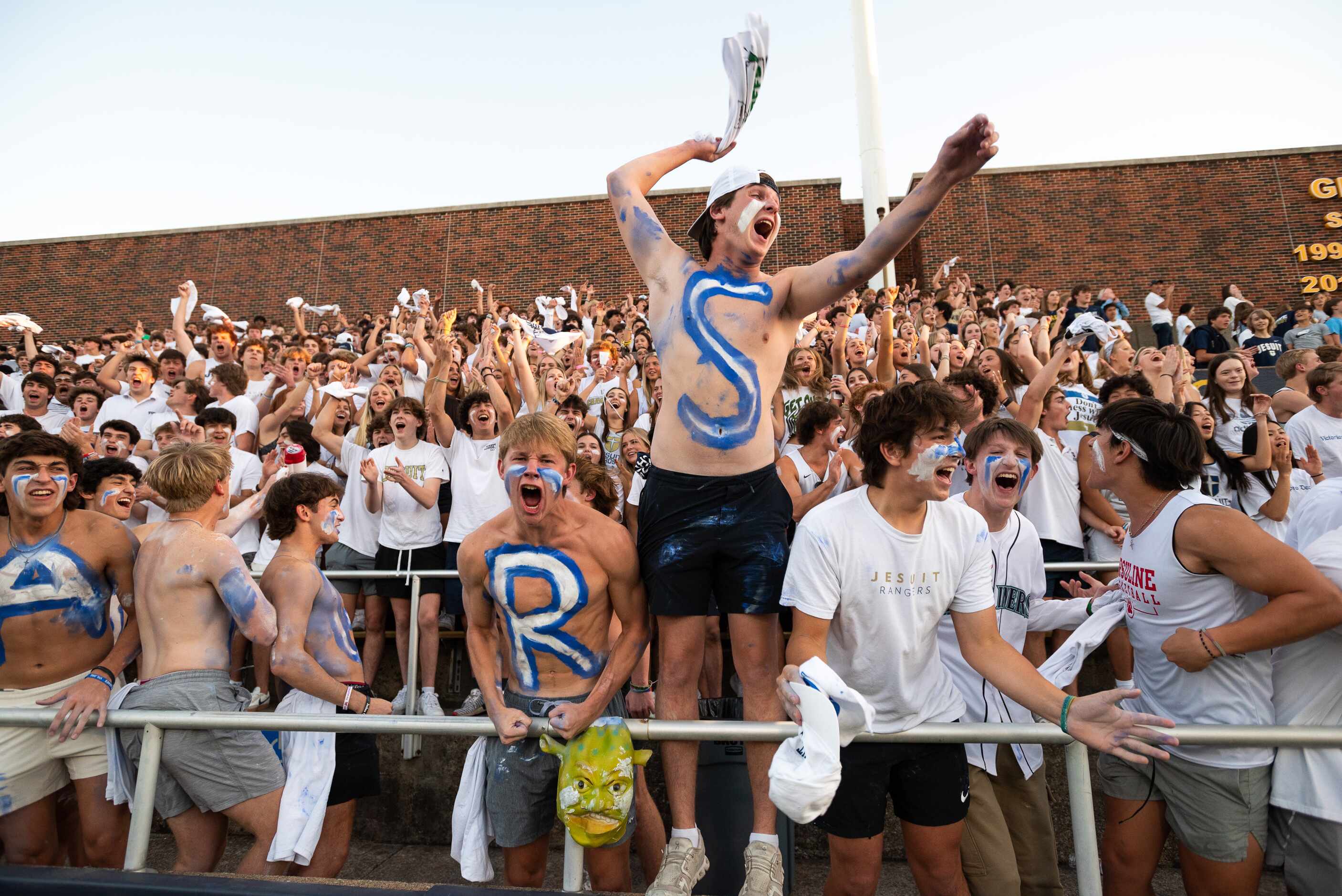 Jesuit students react with excitement during the opening moments of a Friday night high...
