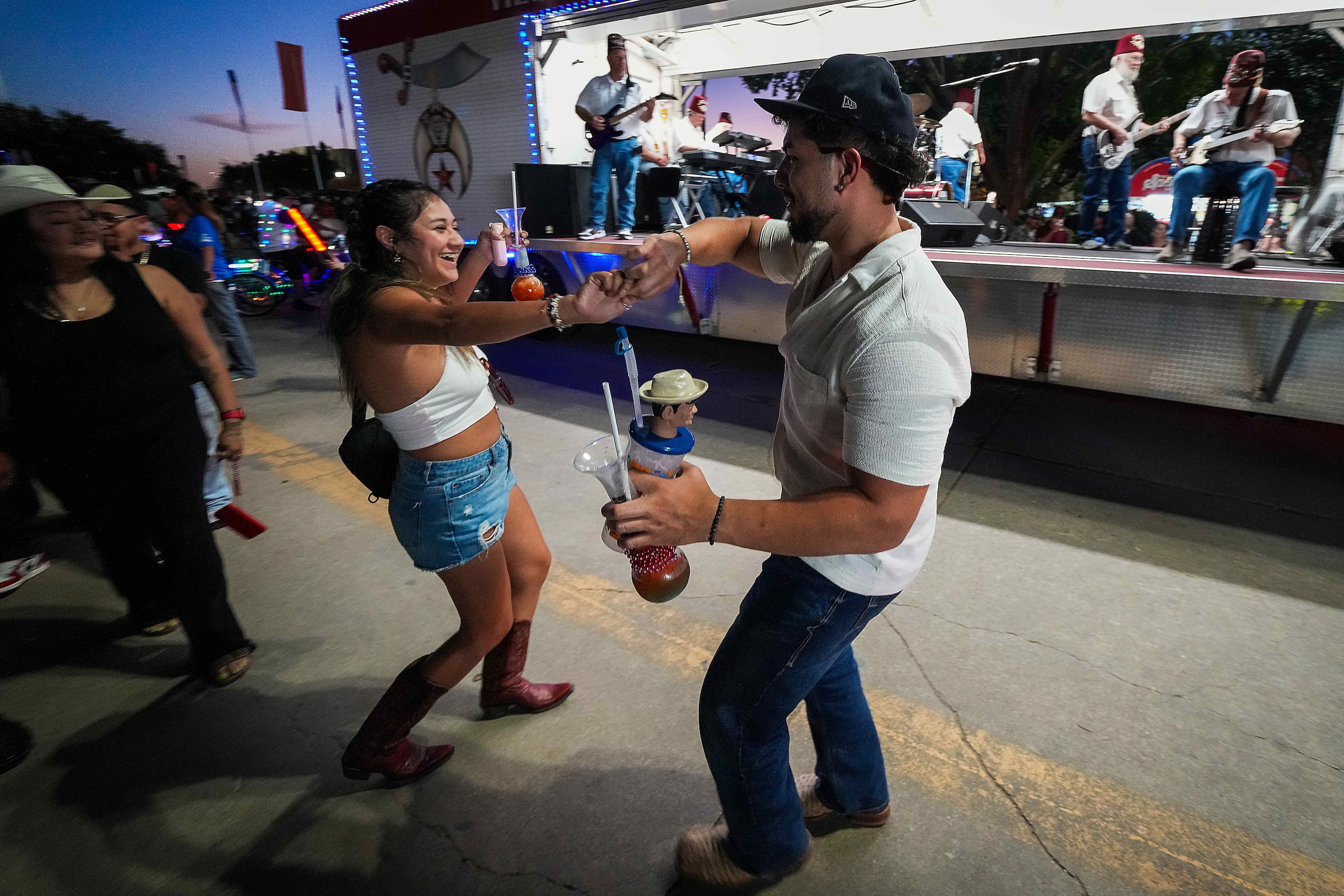 Fairgoers dance to the Hella Shrine Director's Staff Band as their float passes in the...