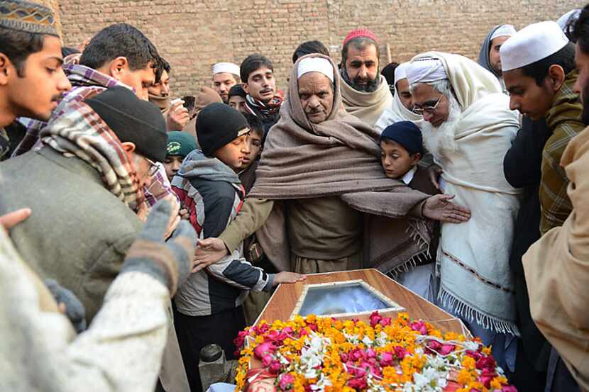 Pakistani mourners gather around a coffin Wednesday during the funeral ceremony for victims...